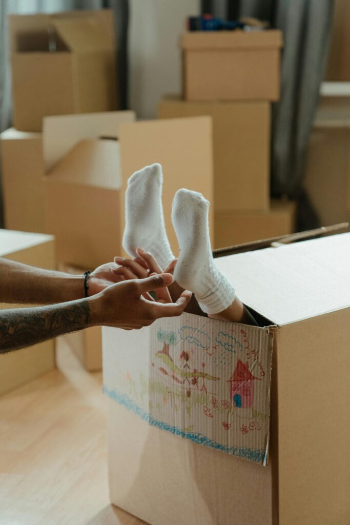 A child's feet in a box filled with drawings, symbolizing fun and creativity during moving.